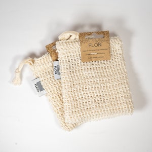 Pode incluir: Duas bolsas de sab&atilde;o de sisal natural com um r&oacute;tulo castanho que diz "FLON Bolsa de sab&atilde;o de sisal natural/Toalha de lavagem Limpeza e esfolia&ccedil;&atilde;o Um produto zero desperd&iacute;cio".
