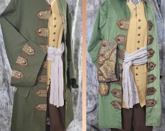 May include: Two pirate-themed costumes on mannequins. One is olive green, the other is a lighter green. Both have gold and brown embellishments, a tan vest, brown pants, and a white sash. The costumes are designed with a historical aesthetic.