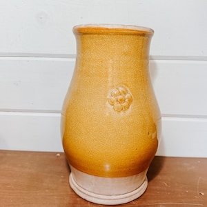 May include: A vintage, yellow-glazed ceramic vase with a crackle finish. The vase features a decorative floral motif and a light beige base. The vase has a rounded body and a slightly flared rim, suitable for displaying flowers or as a decorative piece.