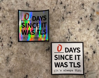 May include: Two stickers with a holographic and white background. Both stickers have black text that reads "0 DAYS SINCE IT WAS TLS (It's always TLS)". The number 0 is in red on both stickers.