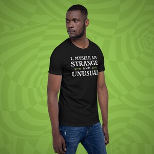 May include: A black t-shirt with white text that reads "I, myself, am strange and unusual".