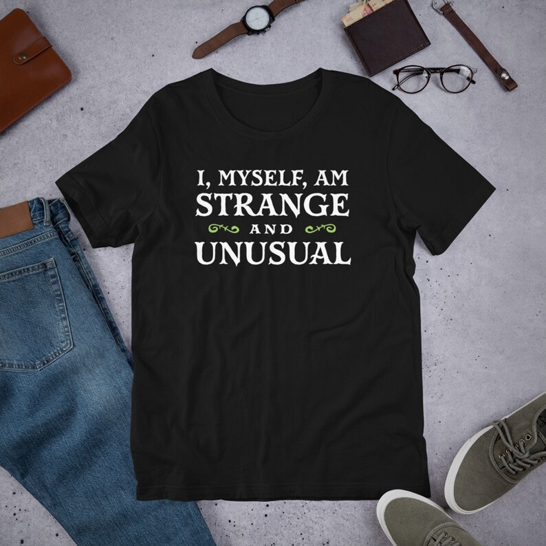 May include: Black t-shirt with white text that reads "I, myself, am strange and unusual" with green decorative flourishes.