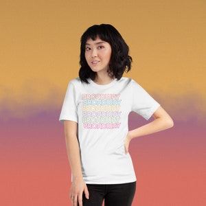 May include: White t-shirt with the word "BROADWAY" repeated five times in a rainbow gradient.
