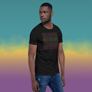May include: A black t-shirt with the word "BROADWAY" repeated in a rainbow gradient pattern.