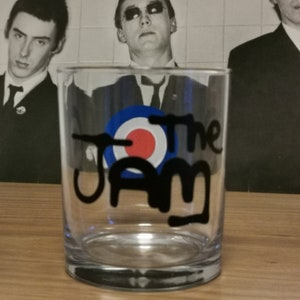May include: A clear glass tumbler with a black and white design of The Jam logo, featuring a red, white and blue target symbol.