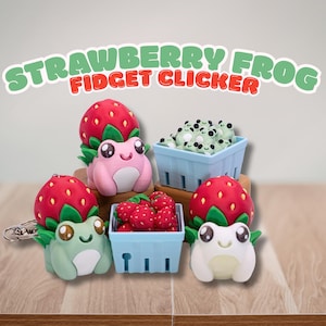 May include: A collection of strawberry frog fidget clickers featuring pink and green frogs with red strawberry caps. Two light blue baskets are included, one filled with tiny green frogs and the other with red strawberries. Text reads STRAWBERRY FROG FIDGET CLICKER.