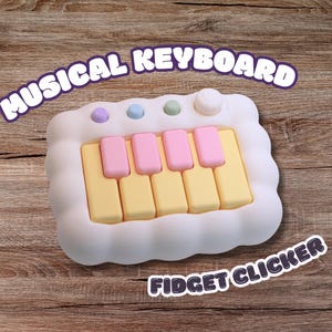 May include: A white musical keyboard fidget clicker with pastel pink and yellow keys. The device features three small circular buttons in purple, blue, and green, along with a larger white circular button at the top right corner of the frame.