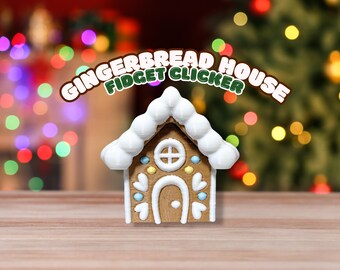 May include: A gingerbread house fidget clicker with white frosting and colorful accents. The house features a door, window, and decorative details. The text "GINGERBREAD HOUSE FIDGET CLICKER" is arched above the house. The background is blurred with Christmas lights.