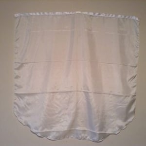 May include: A white satin fabric curtain with a scalloped bottom edge.