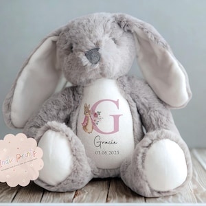 Peut inclure: Une peluche lapin grise avec de longues oreilles et l'int&eacute;rieur blanc. Le ventre du lapin est blanc avec un motif floral rose, la lettre "G" et le nom "Gracie" avec une date. Un jouet en peluche.