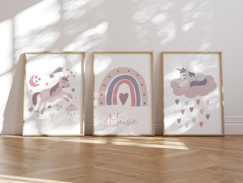 May include: Three framed art prints with a whimsical unicorn theme. The prints feature a unicorn, a rainbow with the name "Maisie", and a sleeping unicorn on a cloud. Soft pastel colors and a wooden frame.