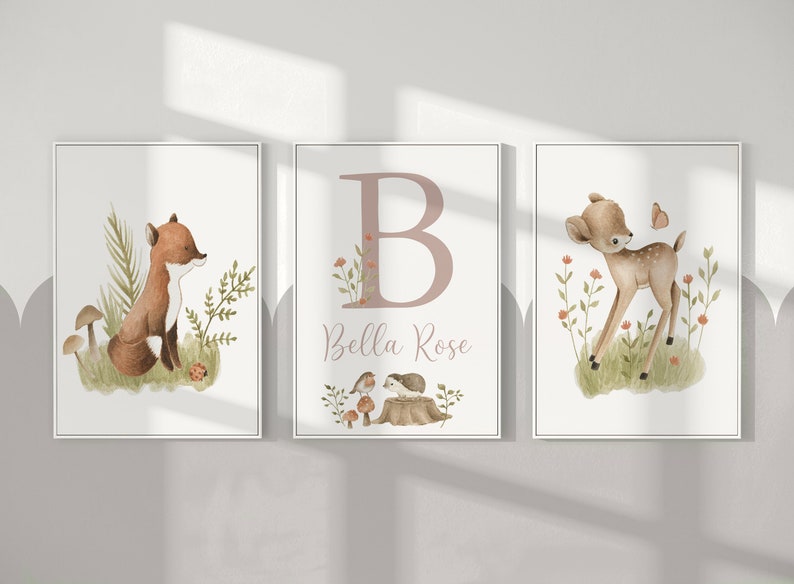 May include: Three framed watercolor prints featuring woodland animals. One print shows a fox, another a deer, and the third a large letter "B" with the name "Bella Rose". The prints have a soft, neutral color palette with green and brown accents.