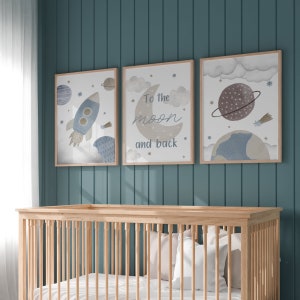 May include: Three framed art prints with a space theme hang above a wooden crib. The prints feature a rocket, a crescent moon with the text "To the moon and back," and a planet. The color palette includes blue, brown, and beige.