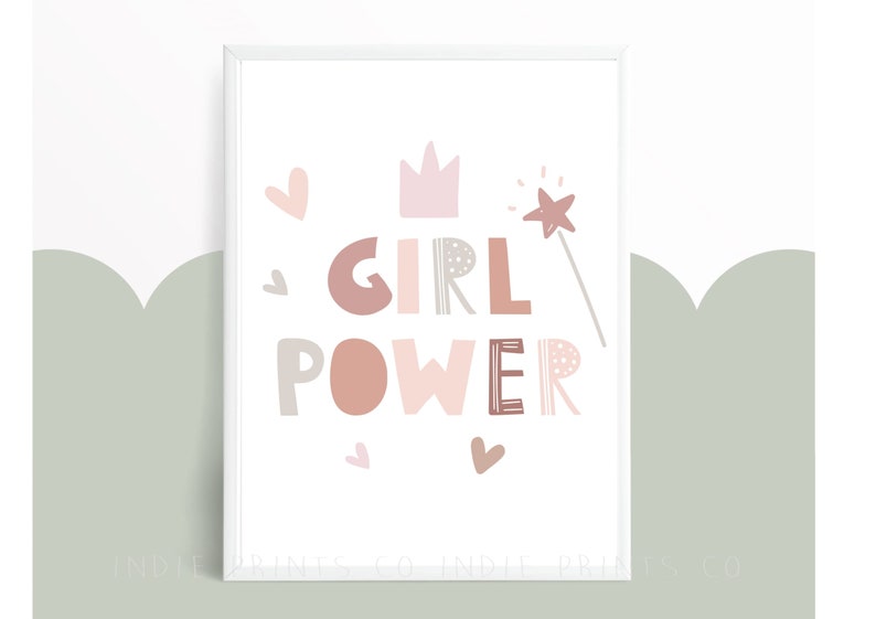 May include: A framed print with the words "GIRL POWER" in various shades of pink and brown. The design includes a crown, hearts, and a star-tipped wand. The background is white with a light green scalloped design.