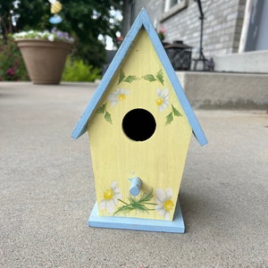 Casa para pássaros com design de jardim e flores em amarelo e azul
