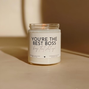 Może przedstawiać: Świeca w przezroczystym szklanym słoiku z białą etykietą. Etykieta głosi "YOU'RE THE BEST BOSS keep that shit up!" czarnym tekstem. Świeca jest ręcznie robiona z wosku sojowego.