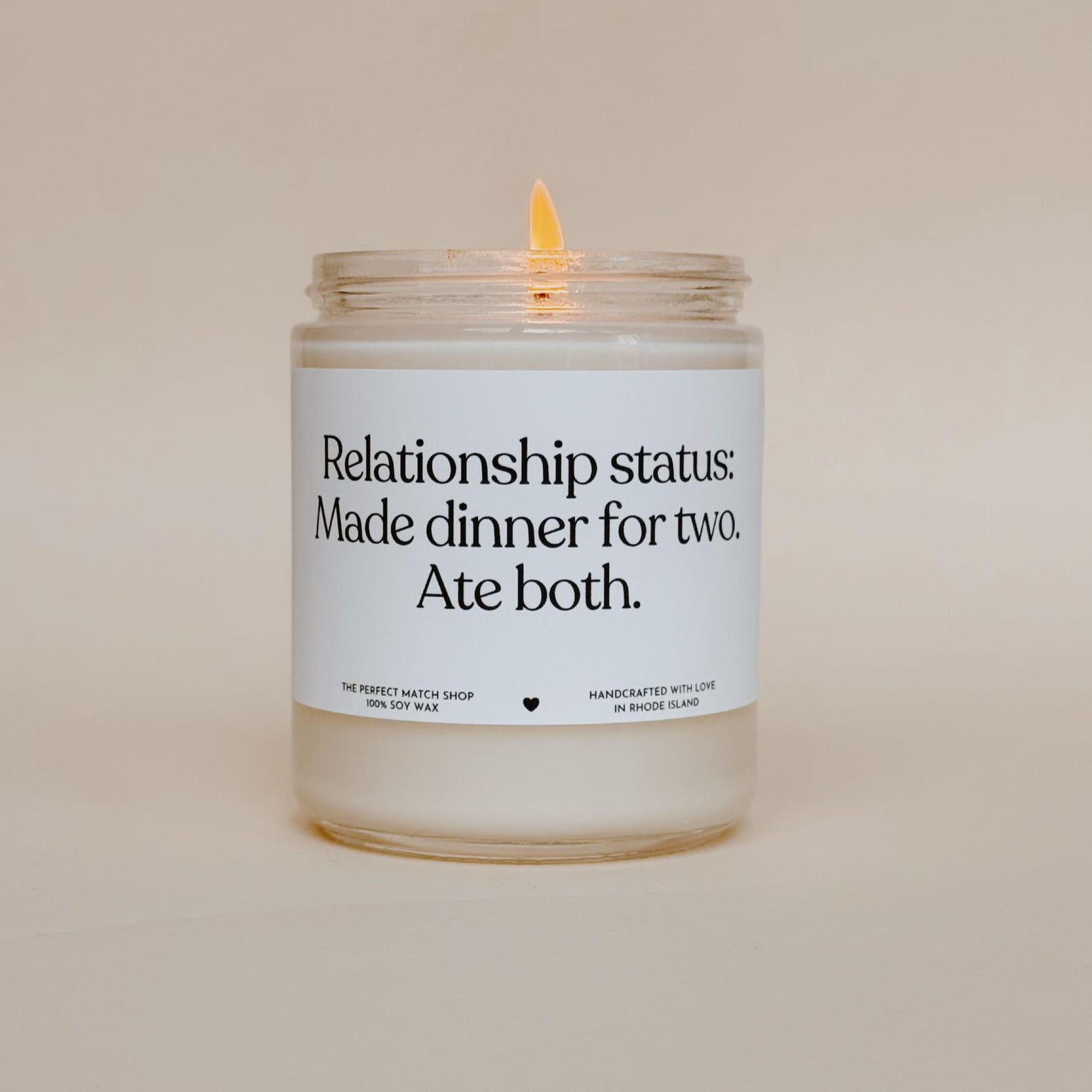 A white candle in a glass jar with a white label with black text