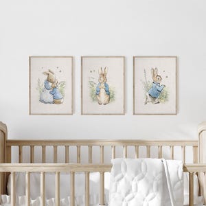 May include: Three framed prints of Peter Rabbit illustrations. The prints are in a nursery setting above a white crib with a white quilted blanket.