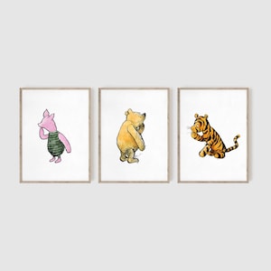 May include: Three framed illustrations of Winnie the Pooh characters. The first frame shows Piglet, a pink pig with a green shirt, looking to the left. The second frame shows Winnie the Pooh, a yellow bear with a red shirt, looking to the left. The third frame shows Tigger, an orange tiger with black stripes, looking to the right.