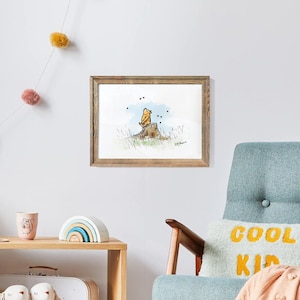 May include: Watercolor art print in a wooden frame. The artwork depicts a bear sitting on a tree stump. The bear is yellow and the tree stump is brown. The background is a light blue sky with some black dots.