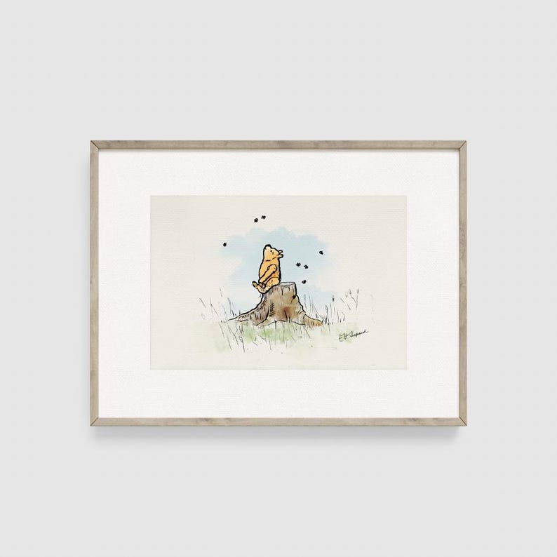 May include: Watercolor illustration of a yellow bear sitting on a tree stump, looking up at black dots. The artwork is framed in a light brown wooden frame.