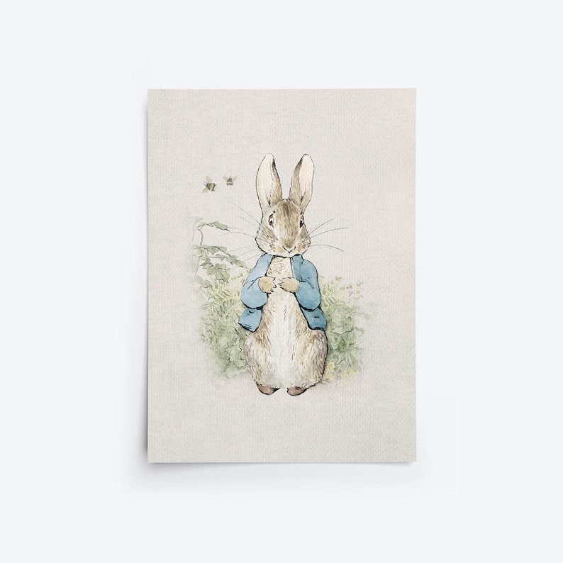 Pu&ograve; includere: Un'illustrazione ad acquerello di Peter Rabbit, un coniglio marrone che indossa una giacca blu, in piedi in un campo di piante verdi con fiori bianchi. Due api volano sullo sfondo.