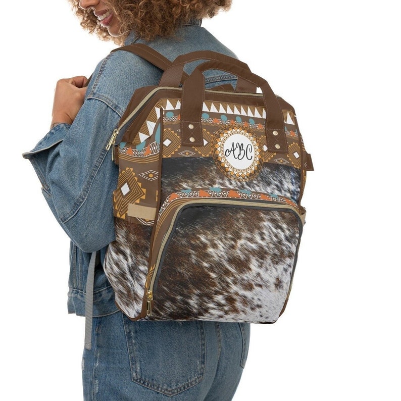 Personalized Distressed Brown and white tricolor faux cowhide tribal turquoise boho western style diaper bag backpack. Custom monogrammed with your name or initials.