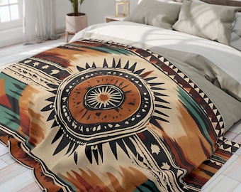 May include: A beige throw blanket with a colourful geometric pattern featuring a large, stylised sunburst design in shades of brown, orange, and teal. The blanket is made of soft, comfortable fabric and is perfect for adding a touch of bohemian style to any room.