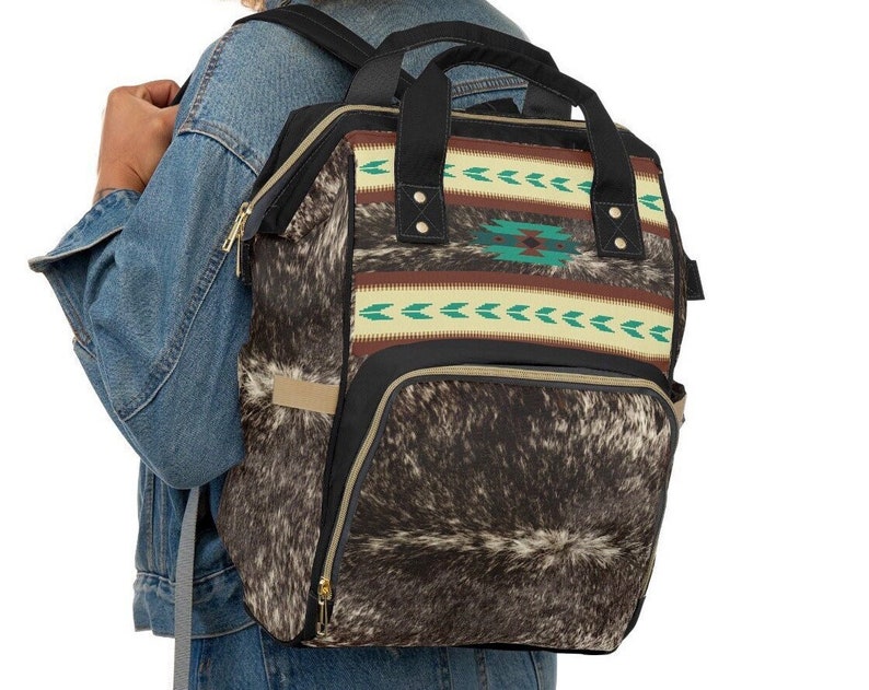 Personalized Brown and white tricolor faux cowhide tribal turquoise boho western style diaper bag backpack. Custom monogrammed with your name or initials. Faux animal print backpack.