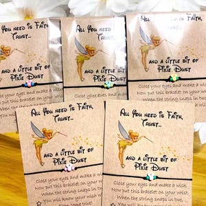 May include: Several wish bracelets on cards with the text "All You Need Is Faith, Trust... And A Little Bit Of Pixie Dust." Each card features a cartoon fairy and a black string bracelet with colorful beads.