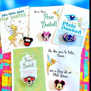 May include: A collection of greeting cards and character-themed accessories. The cards feature Tinkerbell and the phrase "You've Been Pixie Dusted!" along with character-shaped accessories of Minnie Mouse, Stitch, Mickey Mouse, and Tigger.