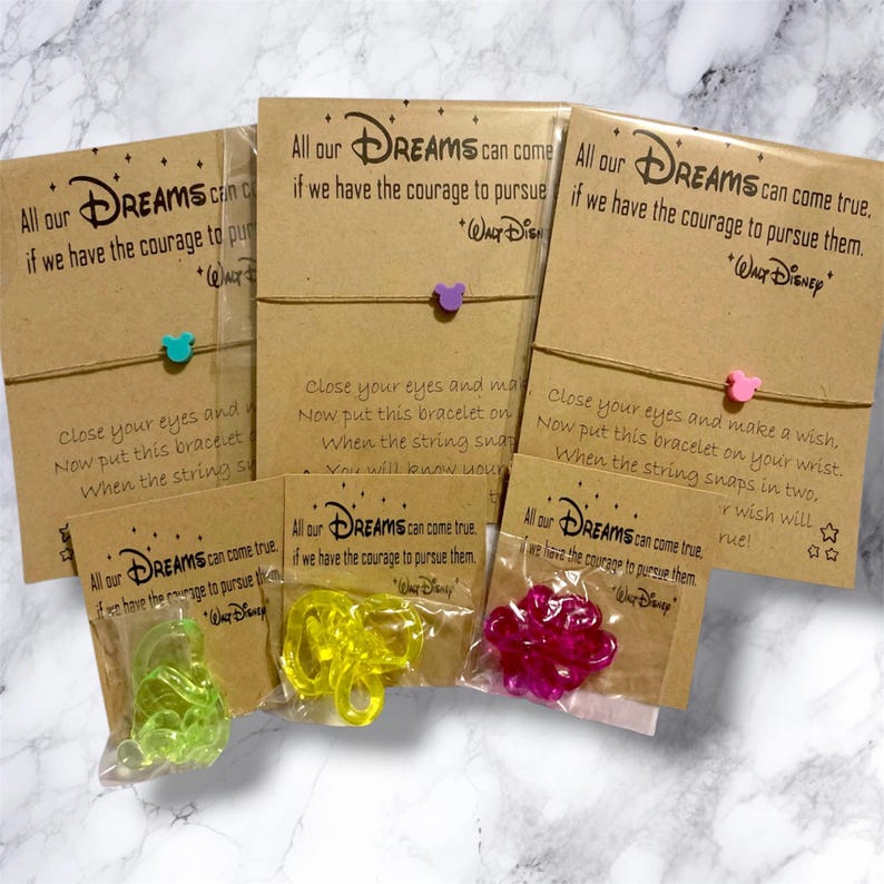 Peut inclure: Plusieurs bracelets &agrave; breloques sur le th&egrave;me de Disney. Chaque bracelet est orn&eacute; d'un petit charm color&eacute; et est attach&eacute; &agrave; une carte avec un texte inspirant. Les breloques ont la forme de t&ecirc;tes de Mickey Mouse et d'autres formes. Les cartes sont marron.