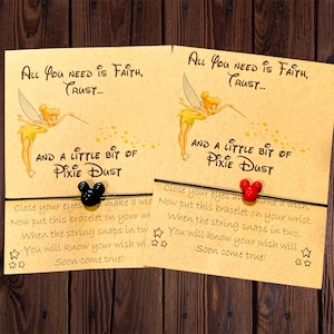May include: Two cards with Tinkerbell illustrations and the text "All You Need Is Faith, Trust... And A Little Bit Of Pixie Dust." Each card has a black or red Mickey Mouse charm bracelet.