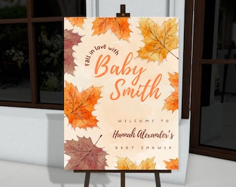 Könnte beinhalten: Ein Willkommensschild für eine Babyparty auf einer Staffelei. Das Schild zeigt herbstliche Aquarellblätter in Orange- und Brauntönen. Der Text lautet "Fall in love with Baby Smith" und "Welcome to Hannah Alexander's Baby Shower."