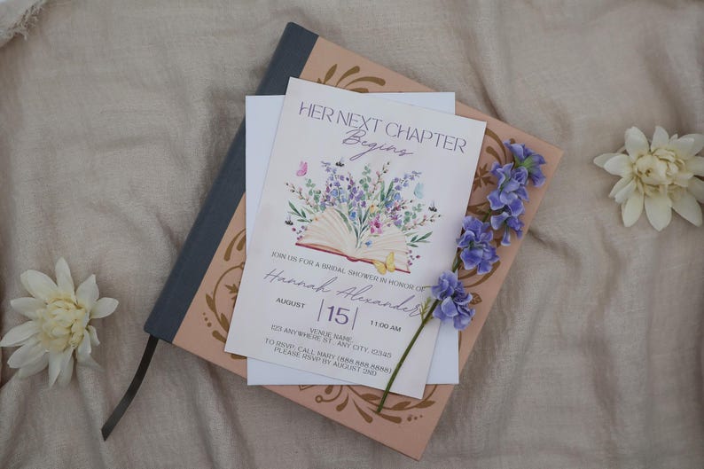 K&ouml;nnte beinhalten: Eine Einladung zur Brautparty mit dem Text "HER NEXT CHAPTER Begins" und Details f&uuml;r Hannah Alexanders Party. Die Einladung zeigt Blumen- und Schmetterlingsillustrationen mit einem Blau- und Rosafarbschema. Ein blaues Notizbuch und Blumen sind ebenfalls vorhanden.