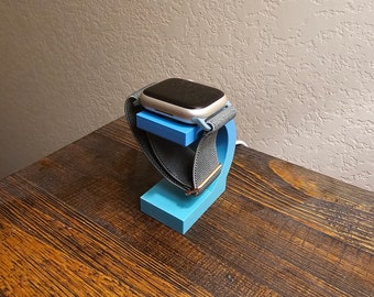 May include: A blue 3D printed watch stand with a gray watch band and a silver watch face.