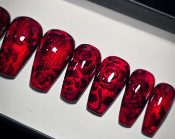 May include: Set of ten red coffin-shaped false nails with a black rose design.