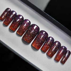 May include: Set of ten false nails with a gradient of red and purple glitter.