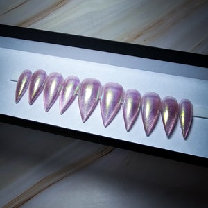 May include: A set of ten iridescent pink false nails with a stiletto shape.