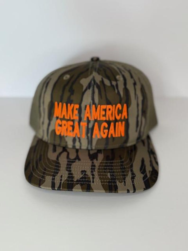 May include: A camouflage baseball cap with the text "MAKE AMERICA GREAT AGAIN" in orange lettering.