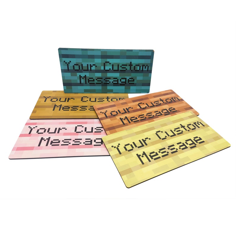 Pu&ograve; includere: Quattro sottobicchieri a tema Minecraft con il testo "Your Custom Message" su ciascuno. I sottobicchieri sono in legno e hanno un design a pixel.