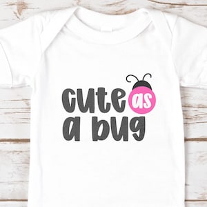 White baby onesie printed with ‘cute as a bug’ using Jelly Puff, a cute chunky handwritten font. Dark gray letters with a pink ladybug ‘as’ circle and tiny antenna. Playful all-caps mix-case style for baby shirts, heat-transfer vinyl, and Cricut/Silhouette projects.