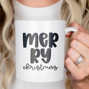 White ceramic mug printed with ‘mer-ry’ in Jelly Puff—bold, rounded letters stacked—plus ‘christmas’ in a small script below. Clean holiday mockup showing the all-caps mix-case chunky style for seasonal mugs and gifts.