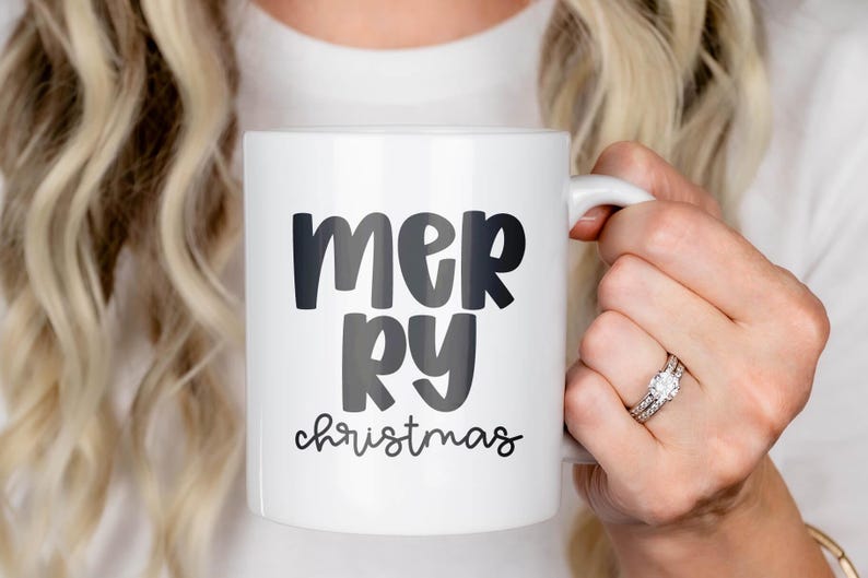 White ceramic mug printed with ‘mer-ry’ in Jelly Puff—bold, rounded letters stacked—plus ‘christmas’ in a small script below. Clean holiday mockup showing the all-caps mix-case chunky style for seasonal mugs and gifts.