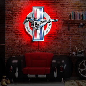 May include: A red illuminated Ford Mustang logo with a chrome finish. The logo is mounted on a brick wall and features a running horse with the words "Ford" and "Mustang" on either side.