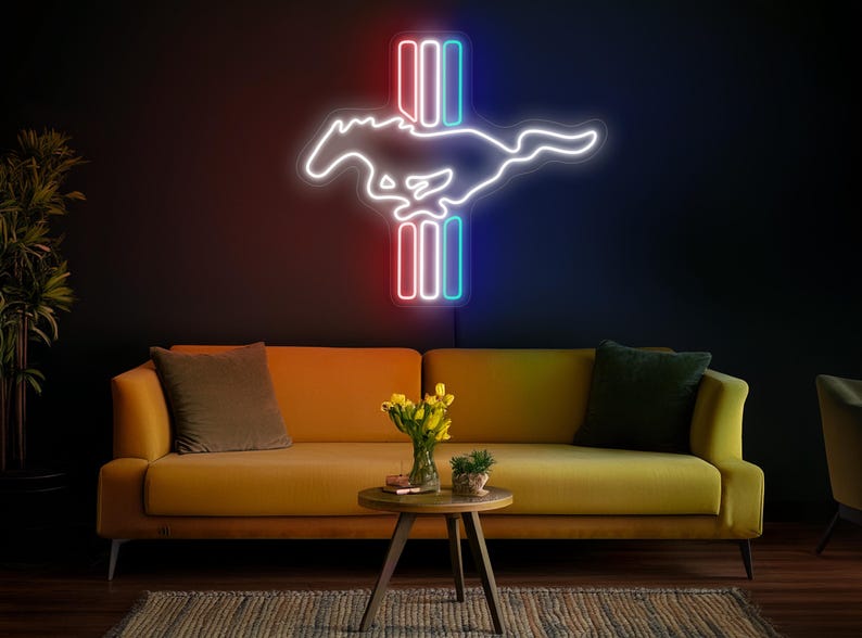 May include: A neon sign depicting the iconic Mustang horse and bar logo. The sign is illuminated in white, red, and blue neon lights. The sign is mounted on a dark wall above a yellow couch.