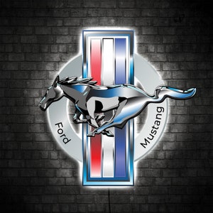 May include: A silver Ford Mustang logo with a black horse running to the right. The logo is on a brick wall background with a white circle around the horse and a blue, white, and red rectangle behind the horse. The words "Ford" and "Mustang" are written on the circle.