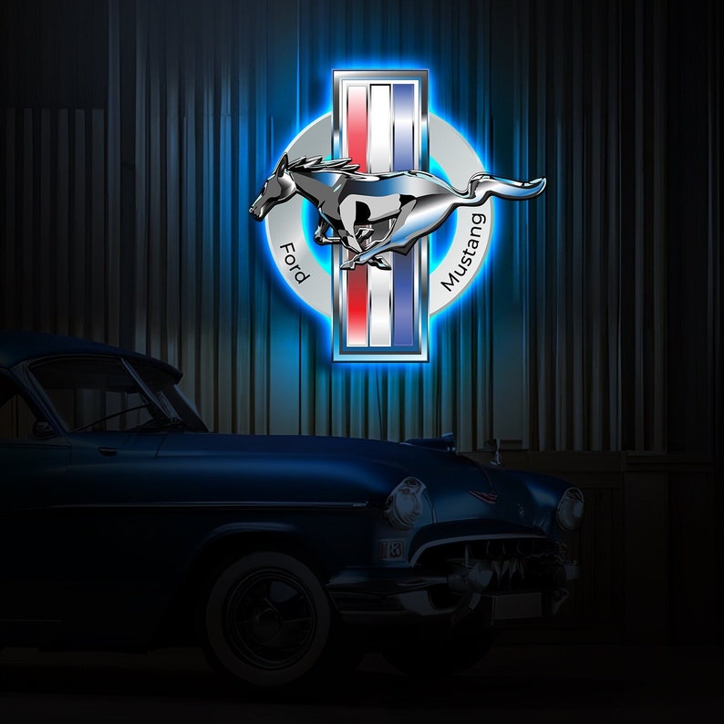 May include: A blue Ford Mustang logo with a silver horse and the words "Ford" and "Mustang" in a circle. The logo is illuminated with blue light and is in front of a dark blue car.