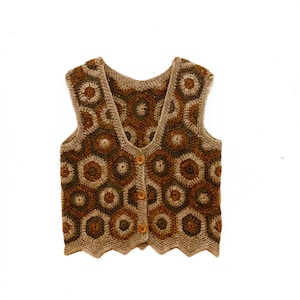Peut inclure: Un gilet crocheté à la main dans des tons marron et beige. Le gilet présente un motif géométrique d'hexagones et se ferme avec trois boutons en bois. Les bords ont un design festonné.