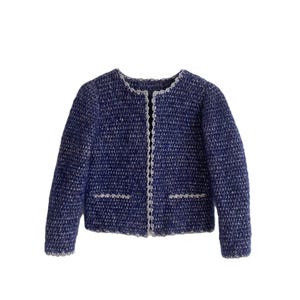 May include: A blue knit jacket with white trim. The jacket has a round neckline, long sleeves, and two front pockets. The trim is along the neckline, front opening, and pockets. The jacket is a solid blue color with white flecks.